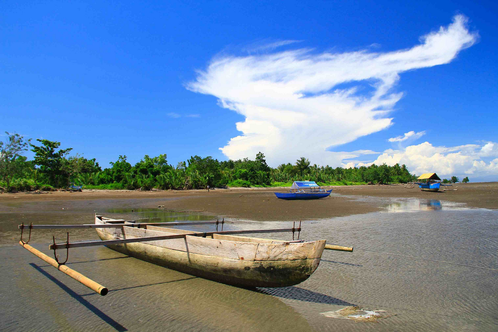 In 1975, Makian's inhabitants were greeted with aplomb in Malifut. Today, their descendants no longer feel welcome. (Yefta Christiono) A small wooden boat is docked on the shore, with two others in the background, in Malifut, North Halmahera. (Yefta Christiono)